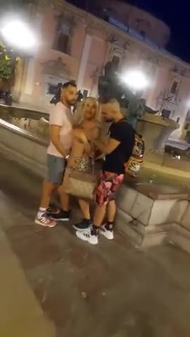 Una sexy puttana viene palpeggiata da due uomini in pubblico